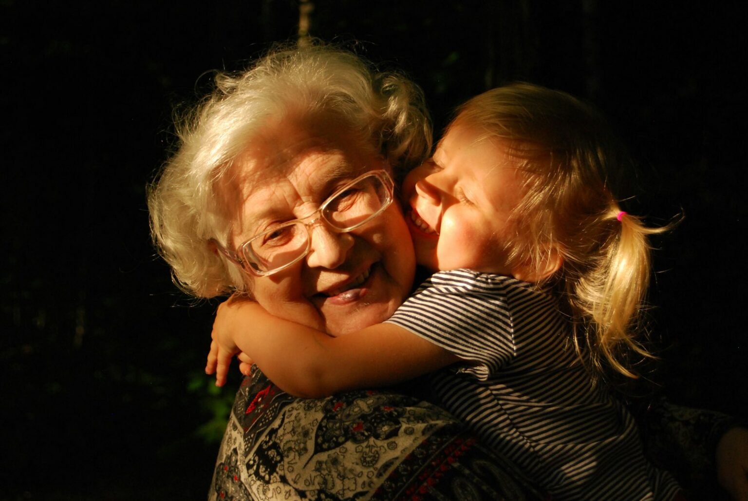 Elderly woman with white hair hugging her adult daughter