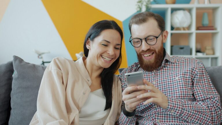 Couple smiling while looking at a smartphone together
