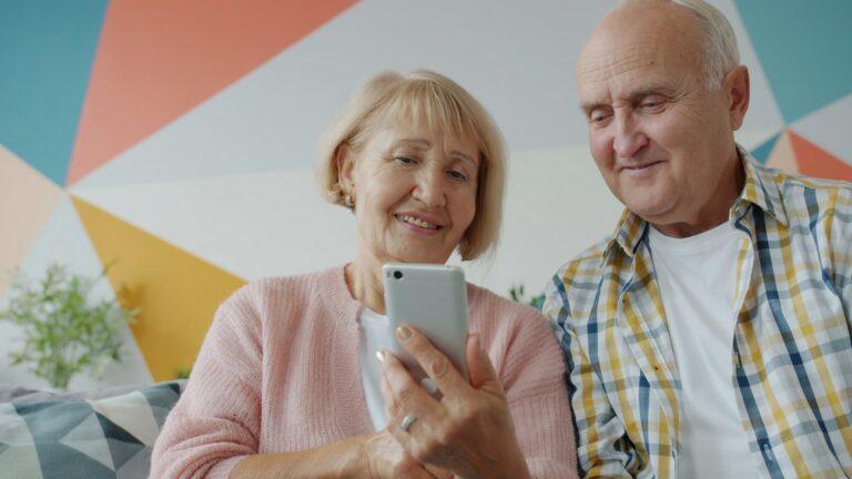 Senior couple smiling while using a smartphone together