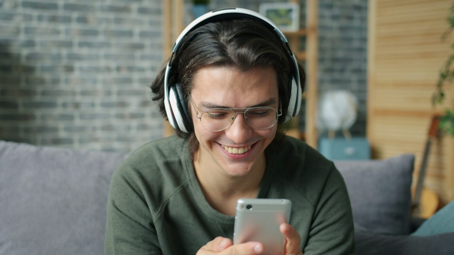 Smiling young man with headphones looking at his smartphone
