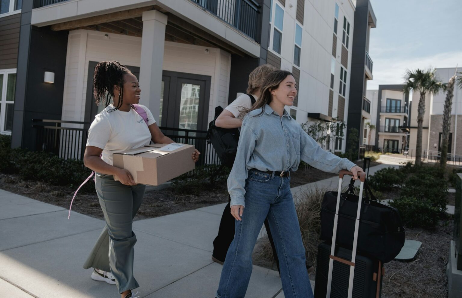 Young people carrying moving boxes into a new apartment building