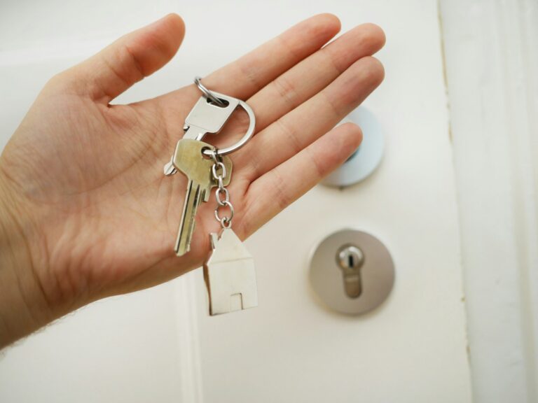 Hand holding house keys next to a front door lock