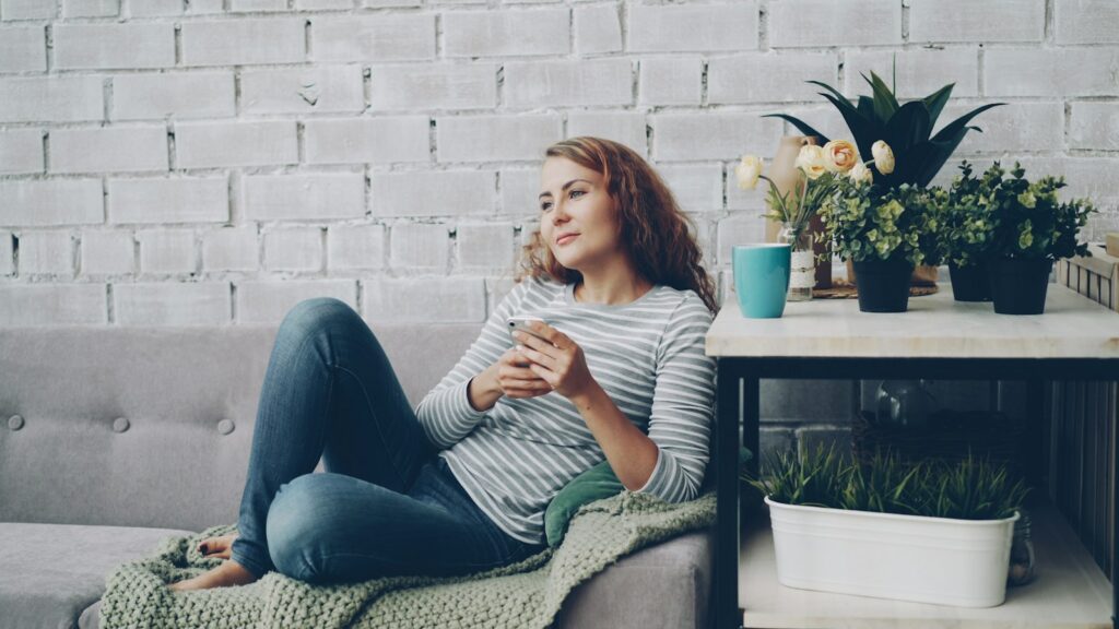 Woman relaxing on the couch with her phone and a cup of coffee