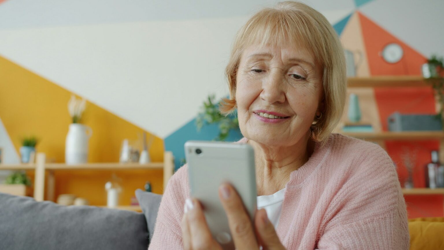 Senior woman smiling while looking at her smartphone